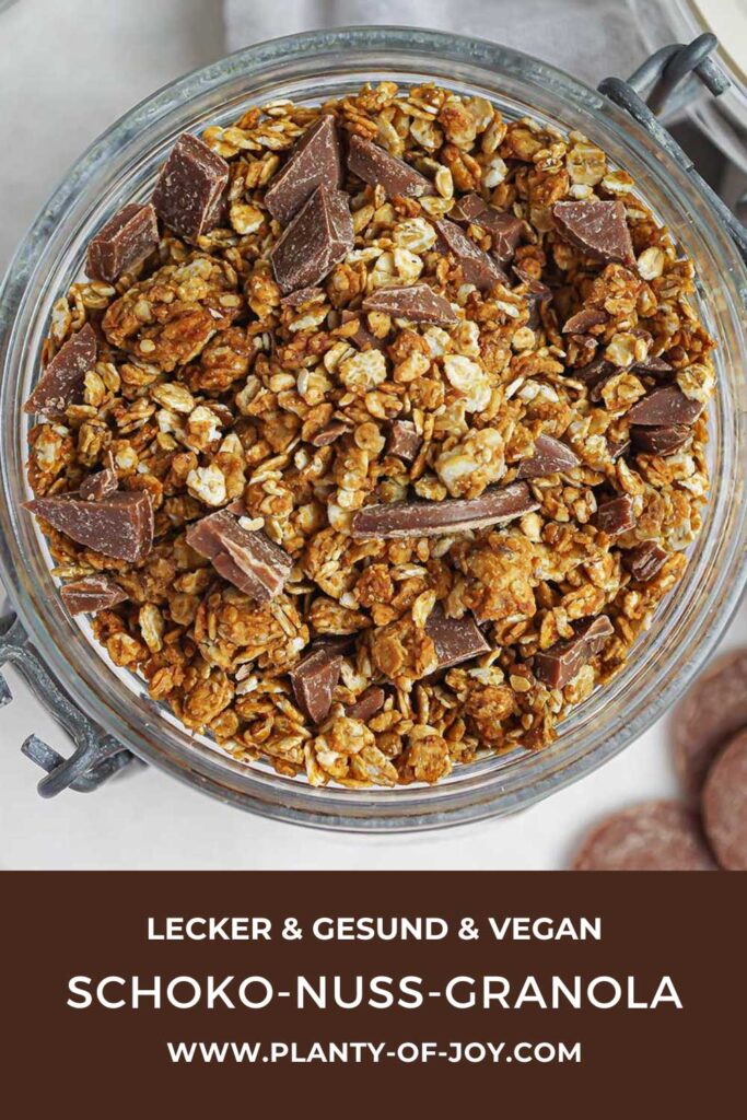 Eine Nahaufnahme von einem Schoko-Nuss-Granola getoppt mit gehackter Schokolade in einem Weckglas auf hellem Hintergrund. Der untere Teil des Bildes ist dunkelbraun mit weißem Text. Der Text lautet lecker & gesund & vegan, Schoko-Nuss-Granola und die Domain der Website Planty of Joy.