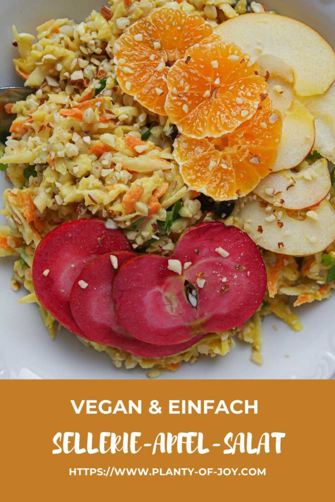 Eine weiße Keramik-Schale mit gelbem Sellerie Salat mit Buchweizen und geraspelter Karotte. Der Salat ist getoppt mit Mandarinen-Scheiben, roten und hellgelben Apfelspalten. Die Schale steht auf einer weißen Steinplatte und neben der Schale liegt etwas frische Petersilie. Im unteren Teil des Bildes ist ein hellbrauner Abschnitt mit weißem Text. Der Text lautet in drei Zeilen vegan & einfach, Sellerie-Apfel-Salat und die url der Website Planty of Joy.