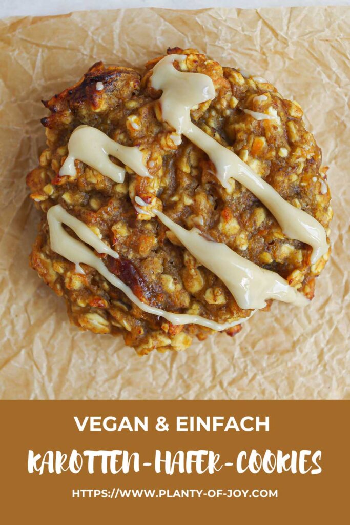 Eine Nahaufnahme aus der Vogelperspektive eines saftigen Karotten-Hafer-Cookies mit Rosinen und Cashewmus-Drizzle. Der Cookie liegt auf zerknittertem Backpapier. Im unteren Teil des Bildes ist ein hellbrauner Abschnitt mit weißem Text. Der Text lautet in drei Zeilen: vegan & einfach, Karotten-Hafer-Cookies und die url der Website Planty of Joy.