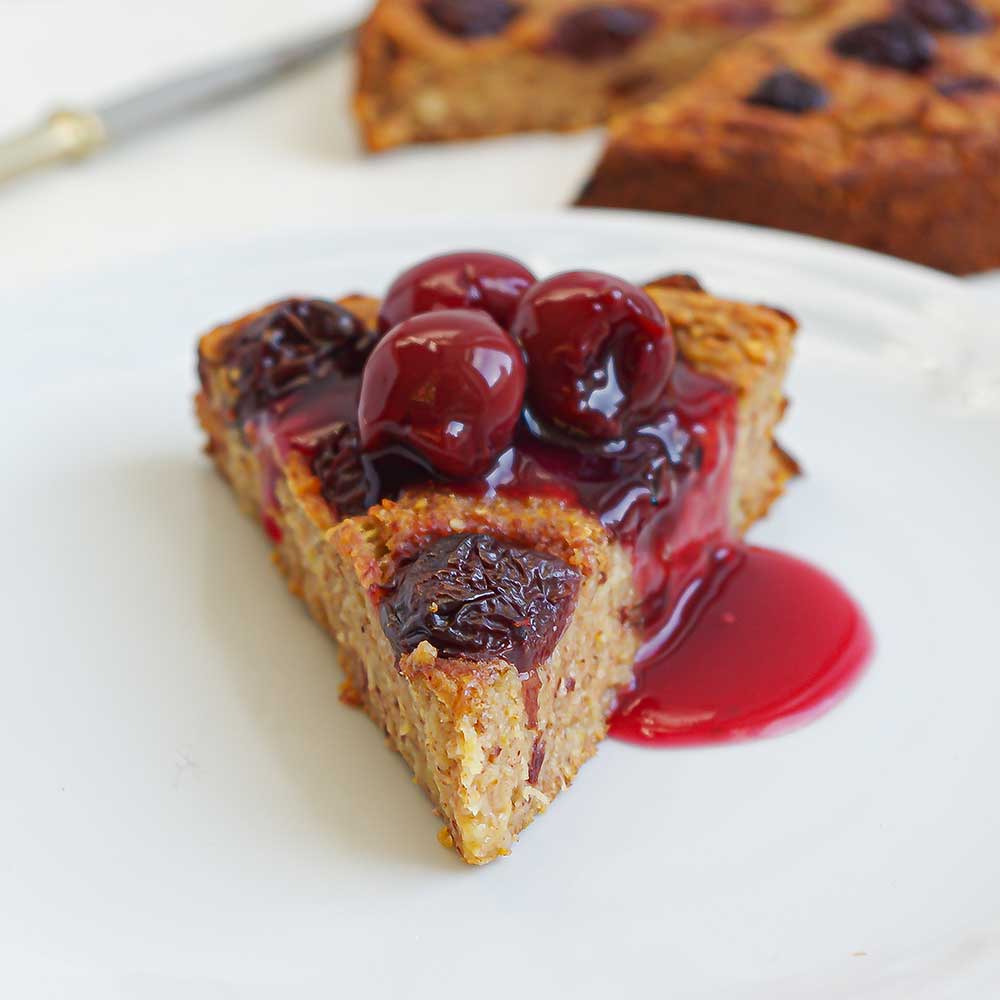 Ein Stück von einem saftigen Apfel-Kirsch-Kuchen getoppt mit eingelegten Kirschen. Der Kuchen sieht sehr saftig und lecker aus.