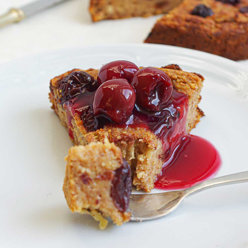 Ein Stück von einem saftigen Apfel-Kirsch-Kuchen getoppt mit eingelegten Kirschen. Der Kuchen sieht sehr saftig und lecker aus.