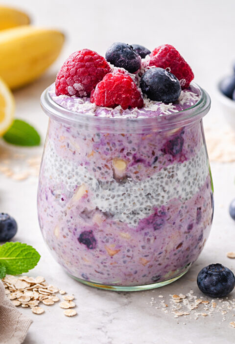 Cremiges Heidelbeer-Chia-Müsli im Glas, getoppt mit frischen Beeren und Haferflocken